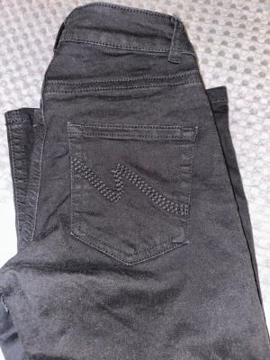 Svarta jeans lågmidjade jeans från Nelly Jeans - Säljer ett par svarta jeans från NELLY med klassisk femficksmodell och snyggt zigzag-mönster på bakfickan. Jeansen har utsvängda ben och lågmidjade och är tillverkade i mjukt denimtyg som sitter skönt. Perfekta för dig som gillar stilrena och tidlösa plagg. Använd endast 1 gång då de är lite långa på mig som är 167cm 