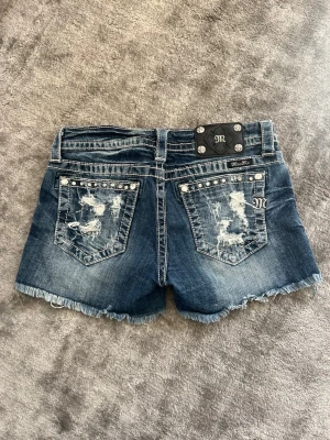 Miss me shorts - Miss me shorts med stjärnor och ränder på framsidan, samt snygga detaljer på baksidan, även miss me märket bak och ett märke på knappen, samt små fina detaljer som pärlor och gnistrande stenar. De är i storlek 28, motsvarar storlek 36/S!