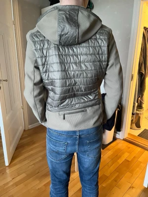 Parajumper Cardigan  - Snygg beige pufferjacka från Parajumpers med quiltad framsida och rygg, huva och dragkedja framtill. Jackan har en gul detalj vid halsen och är tillverkad i syntetmaterial med stickade ärmar. Perfekt för dig som vill ha en stilren och modern look. Den är helt ny aldrig använd men köpt för ett tag sedan som syns på kvittot!!!!! 