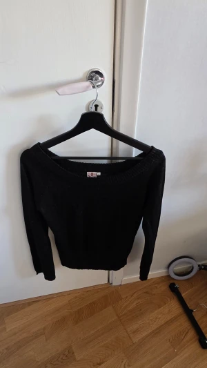 Svart stickad tröja med rund hals - En svart stickad tröja i storlek M med rund halsringning och långa ärmar. Tröjan har ribbstickade muddar vid hals, ärmslut och nederkant. Perfekt för lager-på-lager och enkel att matcha med olika outfits.