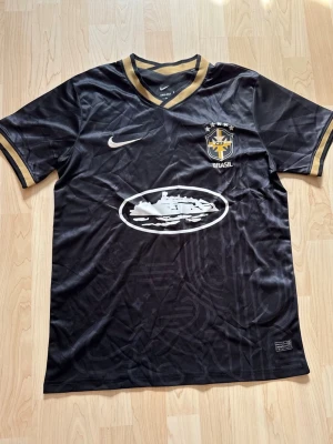 Brasilien x Corteiz Alcatraz Black And Gold Special Edition - Stilren fotbollströja i helt nytt skick. Tröjan är inte använd en endaste sekund.