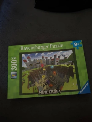 Ravensburger Minecraft pussel - Ett färgglatt pussel från Ravensburger med Minecraft-tema, innehåller 300 XXL-bitar. Kartongen är grön med motiv av ett slott och gräsmatta i klassisk Minecraft-stil. Passar för dig som gillar gaming och utmaningar. Rekommenderad ålder är 9 år och uppåt. 