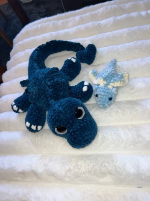 Två söta söta drakar🩵💙 - Dessa urgulliga drakar längtar efter sitt för alltid hem💙🩵🫶🏼✨ Den stora draken  är en mörkblå drake med vita detaljer på tårna, virkat med mjukt garn från Hobbii som heter Baby Snuggle🫶🏼 Den har hårda silvriga ögon som inte går att ta av, sitter som bergen💙🩵 Den är cirka 60 cm lång💙 Bäbisdraken är virkad i baby blå färg med vita detaljer i ett gosigt garn från Tusta som heter Klara🩵🩵 Den har blå ögon som sitter hårt!🩵🩵 Den är cirka 15cm lång🥹🤩