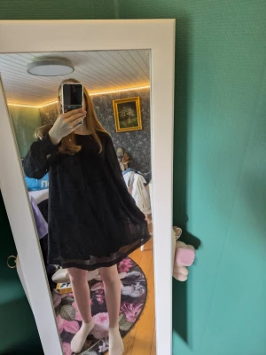 Svart kort klänning från H&M - Svart, luftig och kort klänning från H&M i storlek 34. Klänningen har lång ärm och en lös passform som ger en avslappnad vibe. Perfekt för dig som gillar enkel och stilren design. Materialet känns lätt och skönt mot huden.