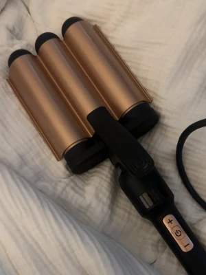  vågtång för hår - Säljer en trippelt vågtång med tre cylinderformade plattor i roséguld och svart handtag. Tången har digitala knappar för temperaturkontroll och lång sladd. Perfekt för att fixa snygga beach waves snabbt och enkelt.