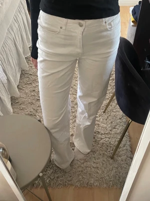 Vita raka jeans med hög midja - Snygga vita jeans med rak passform och hög midja. Klassisk femficksmodell och stängs med knapp och dragkedja. Perfekta för en clean och fräsch look. Materialet ser ut att vara bomull med lite stretch. Har en liten fläck som syns på sista bilden! Längd 34