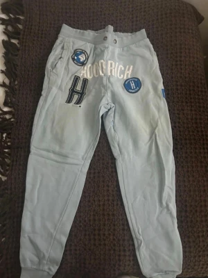 Ljusblå mjukisbyxor Hoodrich - Ljusblåa hoodrich byxor med ett litet hål där under ”H”et på höger lår men skulle nog kunna sy de innan jag säljer de och de är storlek ”S”