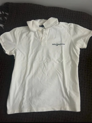 Vit piké från Sail Racing - Fräsch vit piké tröja från sail racing aldrig använd men är i gott skick då jag fick den begagnad och varan är i storlek ”M”