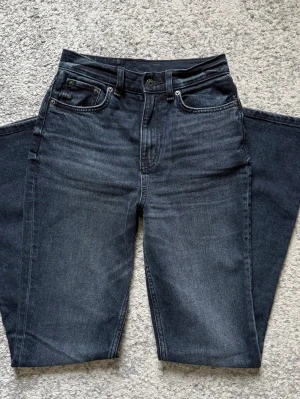Svarta bootcut jeans med mid midja - Snygga svarta bootcut jeans med mid midja och klassisk femficksdesign. Jeansen har en lätt tvättad look och vida ben som ger en trendig siluett. Perfekta för dig som vill ha en cool och avslappnad stil. Innerbensmått 78.