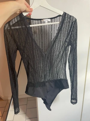 Svart spetsbody från Chiquelle - Snygg svart body i spets från Chiquelle med lång ärm och djup v-ringning 💕