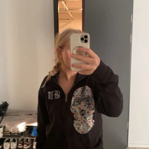 Svart hoodie med glittrig maskdekor (Bvaldi) - Säljer denna snygga zip hoodie med glitterdetaljer från Bvaldi, står även bank robber på ryggen. Storleken är xs/s. Skriv till mig för fler bilder🥰pris kan diskuteras 