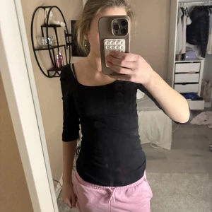 Svart topp med trekvartsärm - En svart, tight topp med trekvartsärm och bred, rundad halsringning. Enkel och stilren modell som sitter snyggt mot kroppen. Perfekt att matcha med både jeans och kjol.