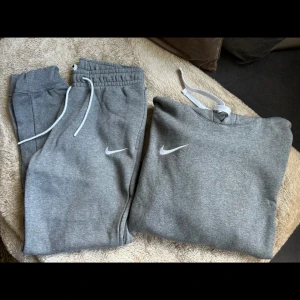Gråa mjukisbyxor från Nike - Säljer ett par gråa mjukisbyxor från Nike med vit snörning i midjan och klassisk Nike-logga på benet. Byxorna har resår i midjan och vid benslut, perfekt för en avslappnad och sportig stil.