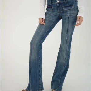 Blå bootcut jeans med fickdetaljer - Snygga blå bootcut jeans med låg midja och coola fickdetaljer framtill. Perfekta för en avslappnad men stilren look. Passar bra till både sneakers och klackar.