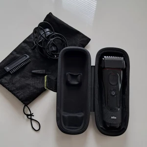 Braun Series 5 Rakapparat - Braun Series 5 rakapparat i fint skick, komplett med laddare, rengöringsborste, skyddsfodral och förvaringsväska. Rakhuvudet och folien ser hela ut, inga synliga skador. Perfekt för en nära och bekväm rakning. Laddkabel och tillbehör medföljer.