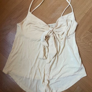 Ljusgul linnetopp med knyt från Gina Tricot - Supersöt beige linnetopp från Gina Tricot i storlek S. Toppen har smala axelband, snygg knytning framtill och en croppad passform som ger en chill vibe. Perfekt för varma dagar och enkel att styla med jeans eller kjol. Endast använd fåtal gånger. Priset kan diskuteras.💕💕