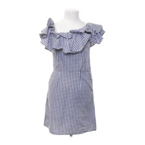 Blårutig offshoulder klänning med volang - Supersöt kort blårutig klänning med offshoulder och bred volang runt halsen. Den har en figurnära passform och är sydd i mjuk bomull. Perfekt för dig som gillar en lekfull och trendig stil med retrovibbar. Rutig design i blått och vitt ger en fräsch känsla.