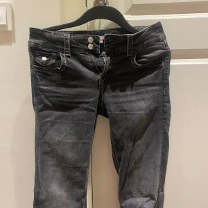 Svarta/mörk gråa jeans  - Snygga svarta/ mörk gråa jeans från Gina Tricot med kontrasterande vita sömmar och dubbla knappar i midjan. 