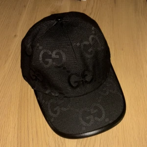 Svart Gucci keps - Snygg svart Jumbo Gucci keps. Den köptes ett tag sen men är inte använd, väldigt fräsch och passar bra på en hel svart outfit för att ge en lyxig vibe!