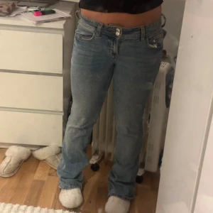 Blå bootcut jeans från H&M Divided - Snygga ljusblå bootcut jeans från H&M Divided i storlek 36. Klassisk femficksmodell med broderad detalj på bakfickan och knappstängning fram. Jeansen har normal passform och är tillverkade i jeansmaterial med lätt tvättad look. Köpte dessa från Plick för ungefär ett par månader sen men jeansen va inte riktigt mina stil så jag väljer att sälja dem. Jag köpte dessa begagnat för 300kr