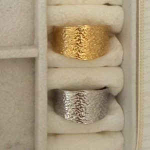 Bred hamrad ring i guld och silver - Två breda ringar med hamrad yta, en i guld och en i silver. Snyggt chunky och unikt mönster som ger cool textur. Perfekt för dig som gillar statement-smycken och vill sticka ut med din stil.