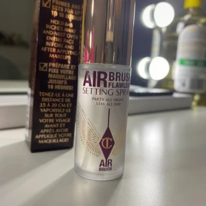 Charlotte Tilbury Airbrush Setting Spray - Airbrush Flawless Setting Spray från Charlotte Tilbury i en lyxig genomskinlig flaska med guldlock och lila detaljer. Innehåller 15 ml och ger en fräsch finish som håller sminket på plats länge. Perfekt att spraya över ansiktet för att fixera din look.