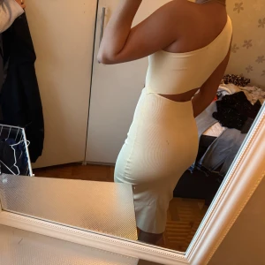 Beige one shoulder midiklänning - Säljer en beige, ribbad midiklänning med one shoulder och cut out-detalj i midjan. Klänningen är figurnära och har en stilren, modern look som passar perfekt för dig som gillar trendiga plagg från Zara .