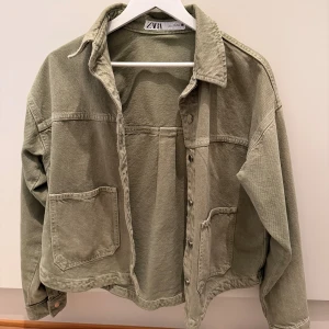 Olivgrön overshirt från Zara - Olivgrön overshirt från Zara i bomull med avslappnad passform. Jackan har stora fickor, klassisk krage och knäppning framtill. Perfekt lager-på-lager-plagg med snygg, enkel design och raka linjer. Använd fåtal gånger, så i superfint skick! 