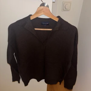 Brun stickad tröja från Lexington - Mysig brun stickad tröja från Lexington i storlek S. Tröjan har en avslappnad krage och långärmade ärmar, perfekt för kyliga dagar. Materialet är mjukt och ger en skön känsla mot huden. En liten Lexington-flagga sitter diskret vid nederkanten.