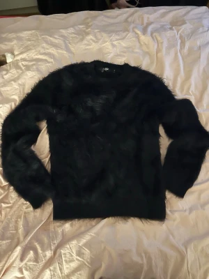 Svart fluffig tröja från Jaded London - Säljer en svart långärmad tröja från Jaded London i storlek S. Tröjan har en fluffig och pälsliknande yta som ger en cool och unik look. Perfekt för dig som gillar statement-plagg och vill sticka ut lite extra.