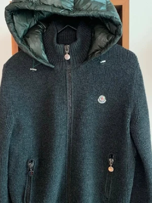 Stickad Moncler Backpadded Cardigan - Säljer denna extremt eftertraktade Moncler cardigan i nyskick (9,5/10)! Storlek M! Nypris 12500. Sällsynt modell, endast seriösa bud. Hör av dig vid eventuella funderingar!