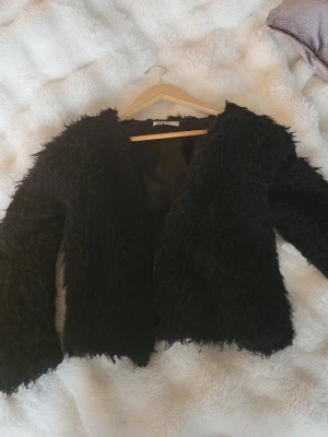 Svart pälsjacka från Gina Tricot - Fluffig svart pälsjacka från Gina Tricot i storlek S. Jackan har långärmade ärmar och en loose passform med mjukt syntetmaterial som ger en cool och trendig look. Perfekt för dig som vill sticka ut med en statement-jacka.