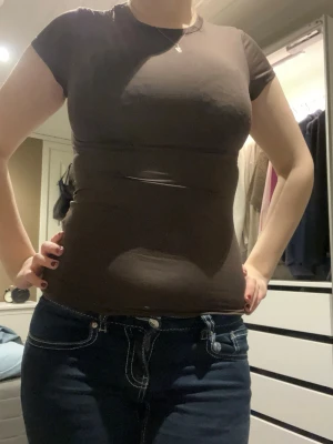 Brun tight t-shirt i bomull - Säljer en enkel brun t-shirt med korta ärmar och rund hals. Modellen är tight och sitter nära kroppen, perfekt för dig som gillar en slim fit. Materialet känns mjukt och stretchigt, troligtvis bomull. Passar till jeans eller shorts för en chill look.