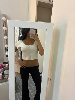 Vit croppad ribbad topp med knappar - Säljer en vit croppad topp med korta ärmar och rund halsringning. 