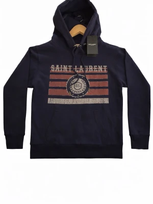 Saint Laurent hoodie - En skitsnygg saint Laurent hoodie i marinblå färg, helt oanvänd med tags kvar. Storlek S och passar slim fit. Tog bort bakgrunden på alla bilder med hjälp av chat gpt så det kanske blev något fel men skriv för mer information eller fler bilder!
