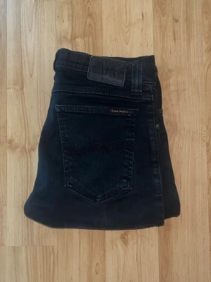 Nudie Jeans - Säljer ett par svarta skinny jeans från Nudie Jeans i modellen Tight Long John. Passformen är slim och materialet är stretchigt jeans för extra komfort. Midja 36cm, längd 103cm. JAG SKICKAR EJ FLER BILDER NÄR JAG BÄR JEANSEN! för bättre inblick i passformen rekommenderar jag att googla på modellnamnet. För storleksguide kolla måtten noggrant då jeansen alltid kan vara uppsydda heller krympta och jag ej tar emot returer :) s5,3