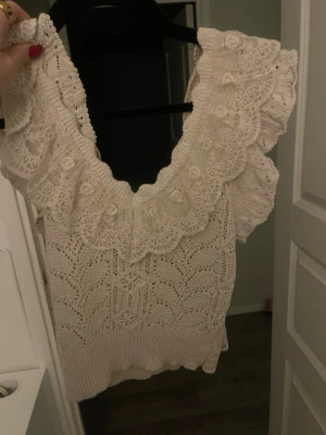Vit spetsig stickad linnetopp från Zara - Supersöt vit linnetopp med bred volangkant i spets och v-ringning. Stickad struktur med fina detaljer och mönster. Användt endast fåtal gånger därför jag säljer den.