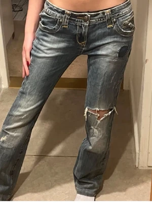 Jättesnygga 200s style jeans! - Säljer ett par jeans från Rock Revival, lowwaist och bootcut. Dessvärre fins det lite småhål vid bakfickorna men annars är de bra!