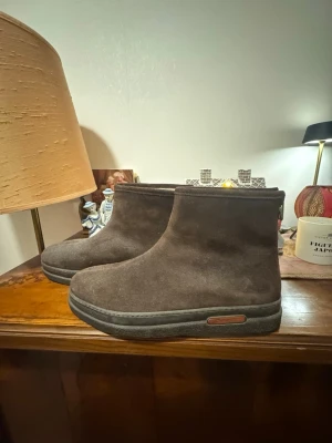 Nya Bruna boots från Gant med ullfoder - Säljer ett par oanvända bruna boots från Gant med mjukt vitt ullfoder på insidan. Skorna har en platt sula och är tillverkade i mocka med en enkel, stilren design. Perfekta för kalla dagar och har en rund tå. Märket syns tydligt på insidan.