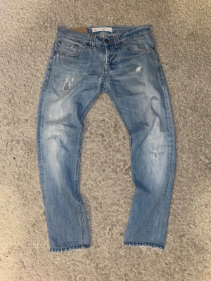 Dondup jeans - Säljer ett par ljusblå jeans från Dondup  med slitna detaljer. Skick 4/5. Ny pris 3500kr. Mitt pris 899kr. Storleken är 29.
