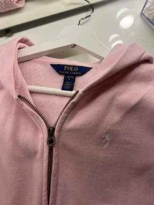 Ljusrosa hoodie från Polo Ralph Lauren - Snygg ljusrosa hoodie från Polo Ralph Lauren. säljer pga den kommer aldrig till användning.  ja köpte den helt ny använd en gång. jättebra skick som ny❤️ skriv om fler bilder 😇😇