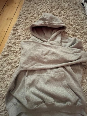 Ljusgrå hoodie med magficka - En enkel och stilren ljusgrå hoodie från lager 157 i storlek S. Hoodien har en stor magficka framtill och en klassisk huva. Tillverkad i mjukt sweatshirtmaterial som är perfekt för chill dagar. Passar dig som gillar basic och bekvämt.