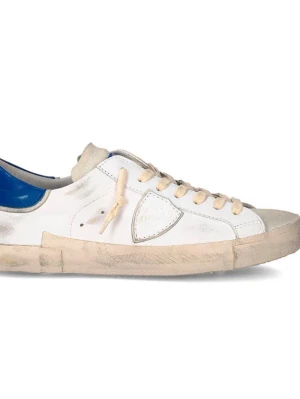 Philippe Model SÖKER BYTE! - Snygga vita sneakers från Philippe Model med beige sula och snörning. Skon har en blå detalj vid hälen och är tillverkad i skinn med mockadetaljer. Klassisk låg modell med rund tå och platt sula.