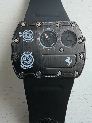 Richard Mille Ferrari svart klocka - Snygg och unik klocka från Richard Mille i samarbete med Ferrari. Klockan har en svart fyrkantig boett med synliga skruvar, detaljer i vitt och en svart gummirem. Swiss made och cool design med tydliga Ferrari-inslag.