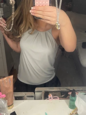 Ljusgrå ärmlös linnetopp - Säljer en stilren ljusgrå linnetopp med halterneck och mjukt fall. Toppen är ärmlös och har en enkel, clean look som passar perfekt till jeans eller kjol. Materialet känns lent och lätt mot huden.