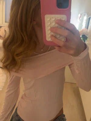 Ljusrosa offshoulder topp - Trendig ljusrosa offshoulder topp med långa ärmar och tight passform. Perfekt att styla med jeans eller kjol för en snygg look. Mjuk och stretchig känsla, passar dig som gillar en feminin och enkel stil.