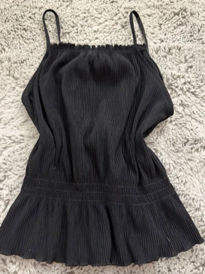 Svart veckat linne - Ett svart veckat linne som ”är spänt” vid magen. Från Kappahl i storleken 146-152. Använt men inga som helst tecken på det.