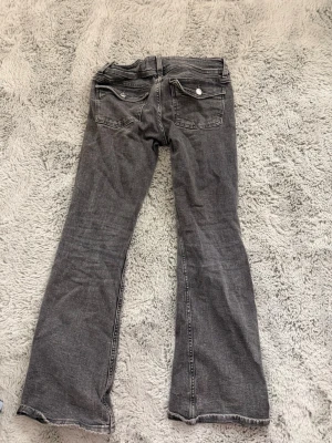 Gråa lågmidjade utsvänga jeans  - Lågmidjade, utsvängda, gråa jeans ifrån Gina tricot i storlek 152. Används men inga större tecken på det. Säljer för att de är för små. 