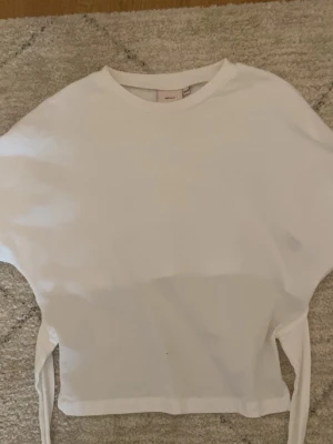Vit tröja från Nelly (xxs) - Säljer en nästan helt oanvänd topp från Nelly i storlek xxs, tröjan är öppen i ryggen och man knyter den där bak, jätteskön och snygg till sommaren/våren