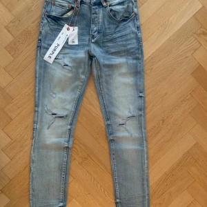 Ljusblå ripped jeans från Purple Brand - Snygga ljusblå jeans från Purple Brand med slitna detaljer och ripped look på benen. Jeansen har slim passform.